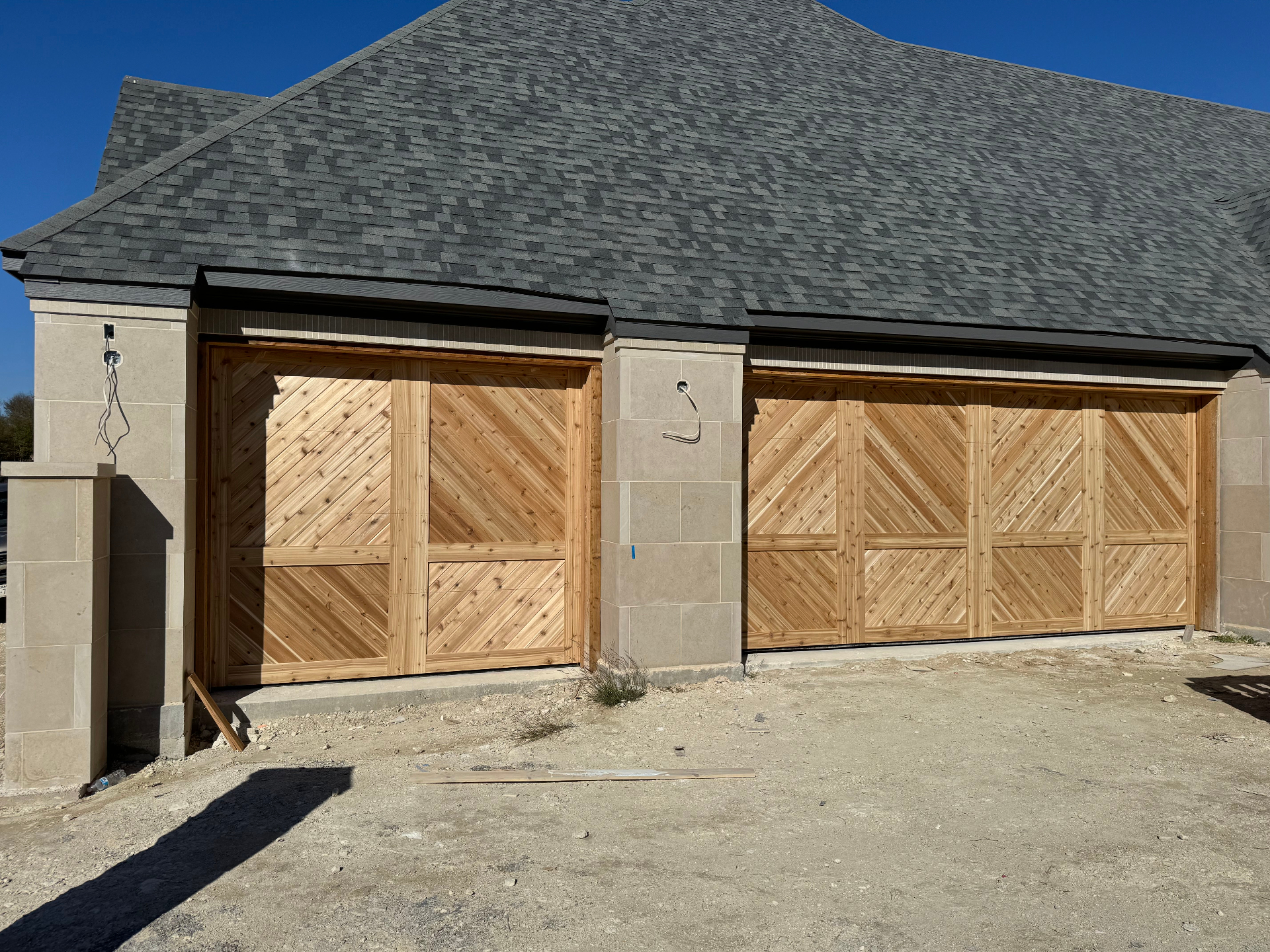 Chevron-pattern wood garage doors on a stone facade
